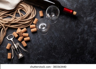 Wine, glasses and corkscrew over stone background. Top view with copy space