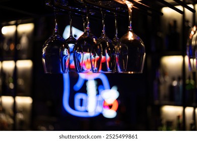 Wine glasses hanging upside down from rack in restaurant or bar with dark background. - Powered by Shutterstock