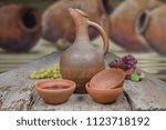 A wine jug and set of clay cups on the wooden table