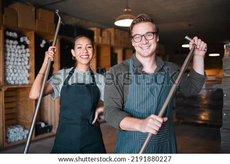Wine making workers with press tool or equipment inside a cellar, winery or distillery warehouse with bulk quality alcohol. Woman, man or sommelier people with smile portrait for industry background