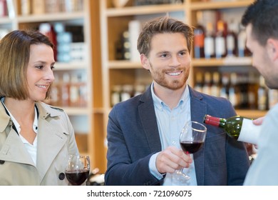 Wine Merchant Pouring Wine For Couple To Sample