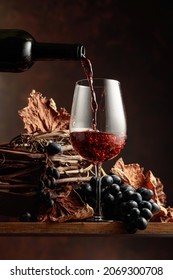 Wine is poured into a glass. Red wine and bunch of grapes on vintage wooden table. - Shutterstock ID 2069300708