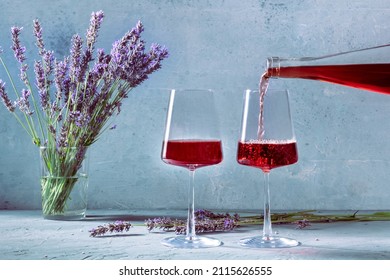 Wine Poured Into Glasses From A Bottle, With Lavender Flowers In The Background. A Tasting Of Provence Wines