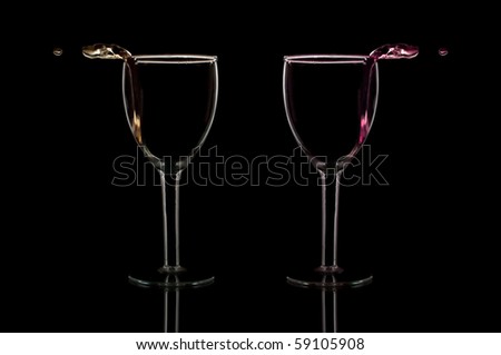 wine pouring out of glasses isolated on black