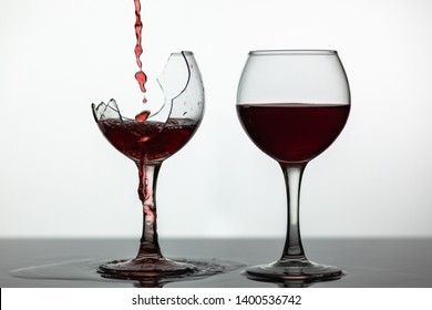 Wine. Red wine pouring into broken wine glass on the wet surface. Rose wine pour. Close up shot. White background - Powered by Shutterstock