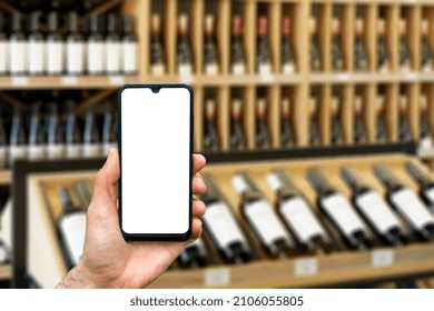 Wine Shop With Bottles Background. Hand With Blank Smartphone Screen One Wine Backdrop. Buying And Ordering Alcoholic Beverages Online