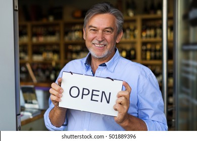 Wine Shop Owner Holding Open Sign
