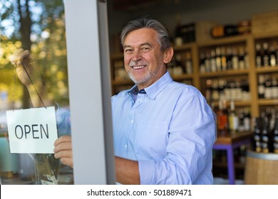 Wine Shop Owner Holding Open Sign
