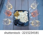 Wine tasting at the Valley of the Beautiful Women in Eger, Hungary. Six glasses of white and rose wines and a cheese plate with grapes. The white wines are of Leanyka and Olaszrizling varieties.