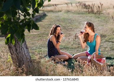 Wine Tasting Young Women During A Picnic In Golden Evening Light