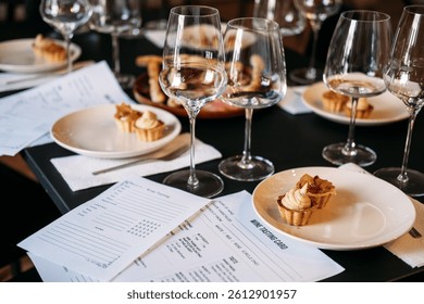 Wine workshop table set with tasting cards, desserts, and multiple glasses prepared for sensory exploration. Wine workshop, hands-on wine education, sensory analysis, sommelier training. quality photo