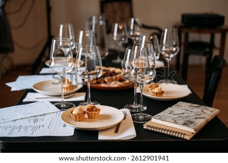 Wine workshop table set with tasting cards, glassware, plated food, and a journal. Wine workshop, food literacy, structured learning, mindful consumption. High quality photo