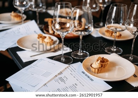 Wine workshop table set with tasting cards, desserts, and multiple glasses prepared for sensory exploration. Wine workshop, hands-on wine education, sensory analysis, sommelier training. quality photo