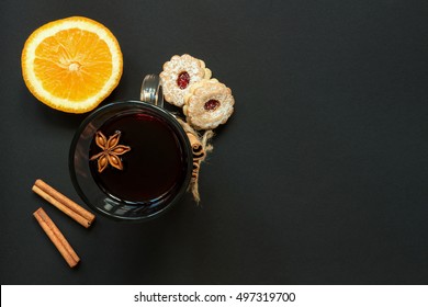 Wineglass Of Hot Wine With Cookies And Orange On The Black Table Top View