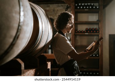 Winemaker Inspecting Bottle of White Wine in Cellar