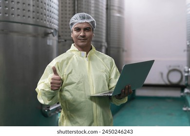 Winemaker inspecting quality the process of fermentation during manufacturing in winery factory and stainless tank. Male winemaker working with laptop computer in winery factory - Powered by Shutterstock