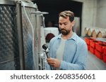 Winemaker standing in the wine cellar, controlling pressure in fermentation tank.