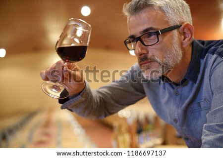Winemaker tasting red wine in cellar