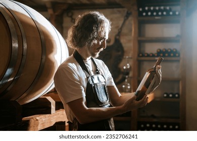 Winemaker tasting wine in a cellar with wooden barrels - Powered by Shutterstock