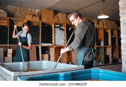 Winemaker workers in the process of making wine with a wine press tool or equipment in a warehouse, winery or distillery. Woman, man or vintner people pressing juice of grapes for alcohol industry - Powered by Shutterstock