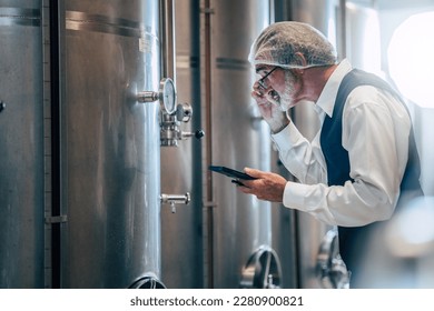 Winemaker working in modern large winery factory liquor drink industry quality and fermentation monitor  - Powered by Shutterstock