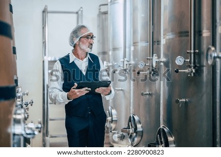Winemaker working in modern large winery factory liquor drink industry quality and fermentation monitor 