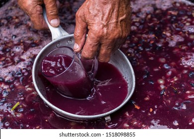 Winemaker's hand with a glass mug, picking up juice from grape must. Wine material, stum, maun. Technology of wine production in Moldova. The folk tradition of making wine.
