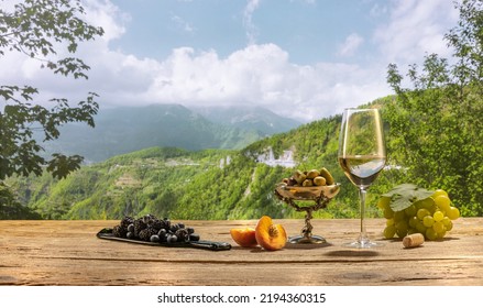 WInemaking. Olives and grapes. Bottle and glass of delicious white wine standing on wooden table on beautiful nature landscape with green garden and vineyard. Bright summer sunny day. Degustation. - Powered by Shutterstock