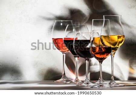 Wines assortment. Red, white, rose wine in wineglasses on gray background. Wine tasting concept. Hard sunlight and shadows from foliage Zdjęcia stock © 