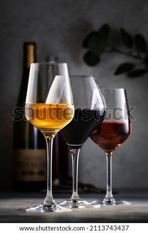 Wines assortment. Red, white, rose wine in glasses and bottles on gray table background. Wine bar, shop, tasting concept
