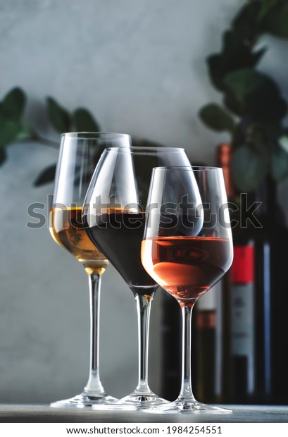 Wines\
assortment. Red, white, rose wine in wineglasses and bottles on\
gray background. Wine bar, shop, tasting\
concept