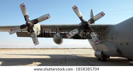 The wing and 2 engines of an unidentified military C-130 Hercules Cargo transport aircraft