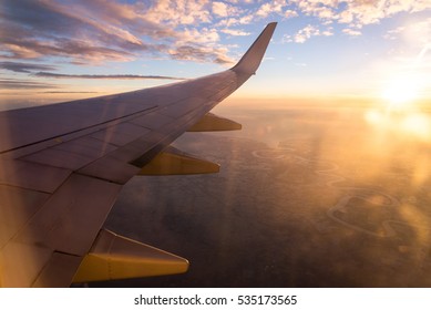 Wing of the air plane on the sea of clouds sunset sky background from window airplane