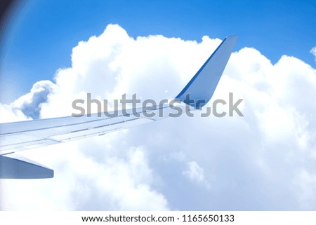 Wing of airplain flying over the clouds with blue sky.