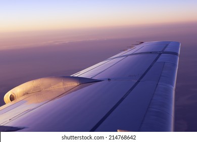 Wing of an airplane flying above the clouds at the sunrise - Shutterstock ID 214768642