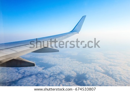 Wing of an airplane flying above the morning clouds