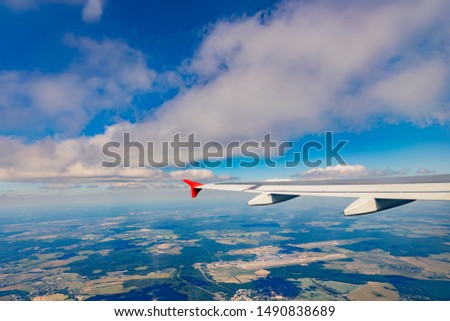 The wing of an airplane flying against the sky over the city. Travel concept.