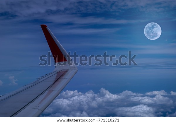 wing of\
airplane and full moon at night and\
cloud