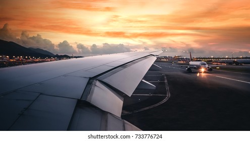 Wing of an airplane taking off on run way in terminal with clouds at sunset, blank copy space