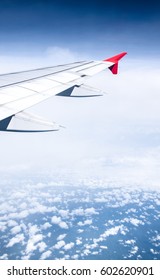 A wing of the airplane while flying over the amount of clouds.
