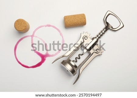 Wing corkscrew, corks and red wine stains on white background, top view