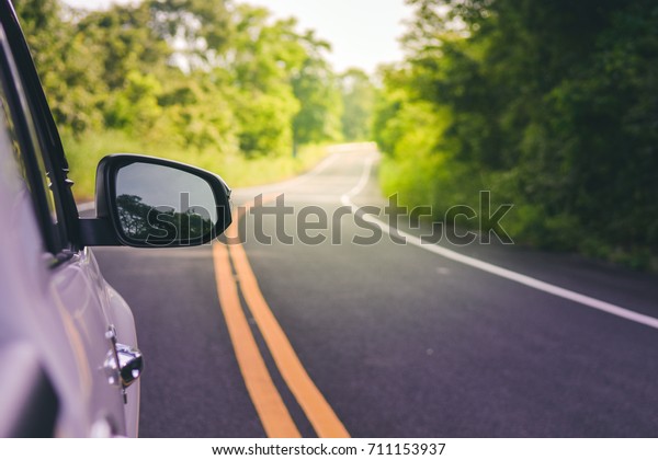 The wing mirror\
of a Car with nature\
street.