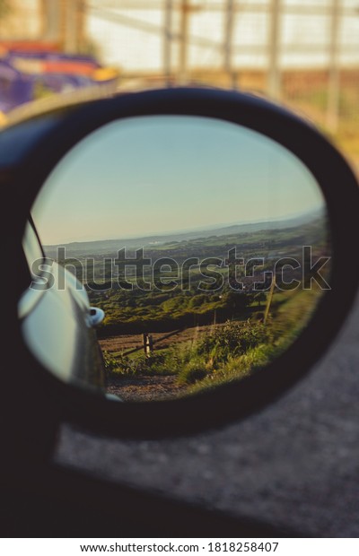 Wing mirror shot from inside car of nature\
whilst travelling