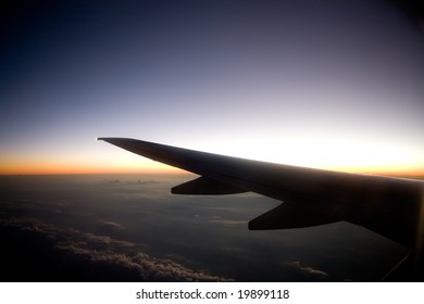 A Wing On An Airplane In Flight At Sunset