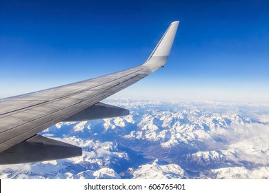  Wing Of The Plane Flying Over Clouds. Massif Below