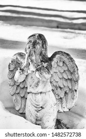 Winged Angel Praying And Partially Buried In Melting Snow Drift