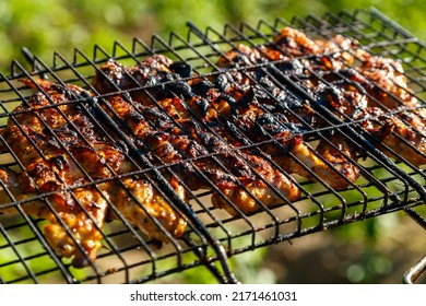 Wings In Marinade And Soy Sauce Are Fried On A Smoky Grill. Horizontal Photo