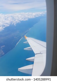 The wings of the plane on a cloud background and the bright sky. To shoot through a plane window