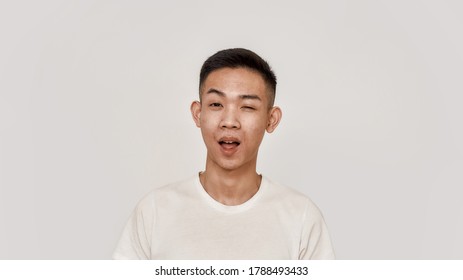 Wink. Portrait Of Young Asian Man With Clean Shaven Face Looking Cheerful, Winking At Camera Isolated Over White Background. Beauty, Skincare, Health Concept. Front View. Web Banner