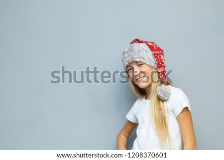 Winking Christmas girl in Santa hat on grey background

